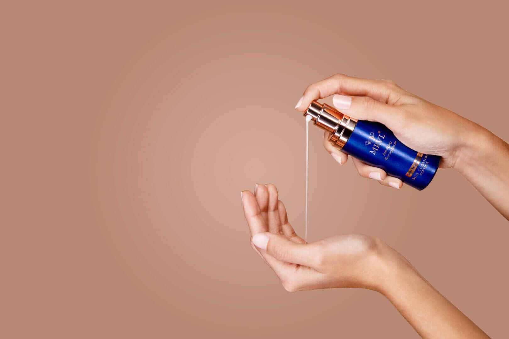 Hands applying a drop of MRVL serum from a blue bottle