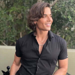 Man with dark hair in a black shirt outdoors