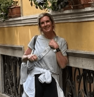Woman smiling outdoors by a yellow wall